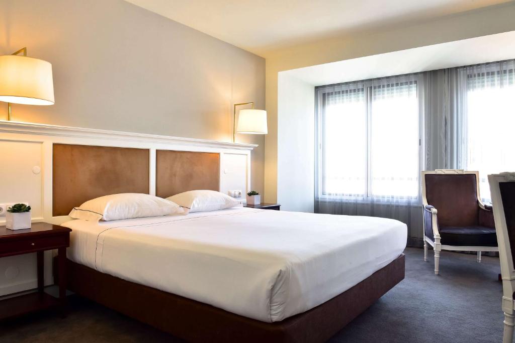 科英布拉Tivoli Coimbra Hotel的酒店客房带一张大床和一把椅子