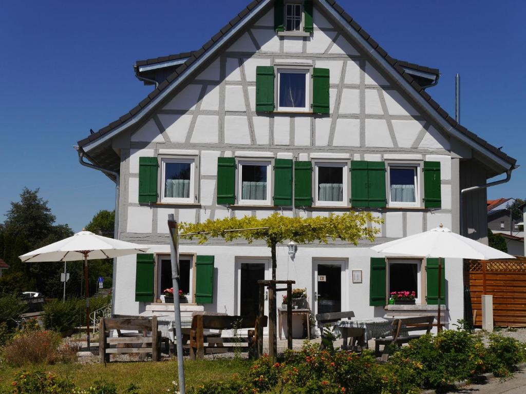 塞勒姆Pension & Café Schlupfwinkel的白色绿色的房子,配有桌子和遮阳伞