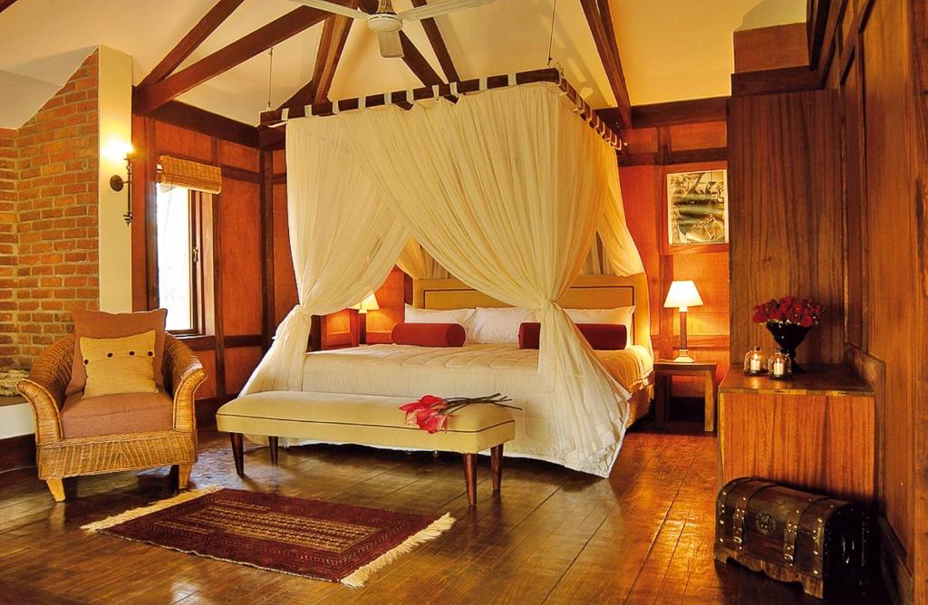 阿鲁沙Elewana Arusha Coffee Lodge的一间卧室配有一张天蓬床和一把椅子