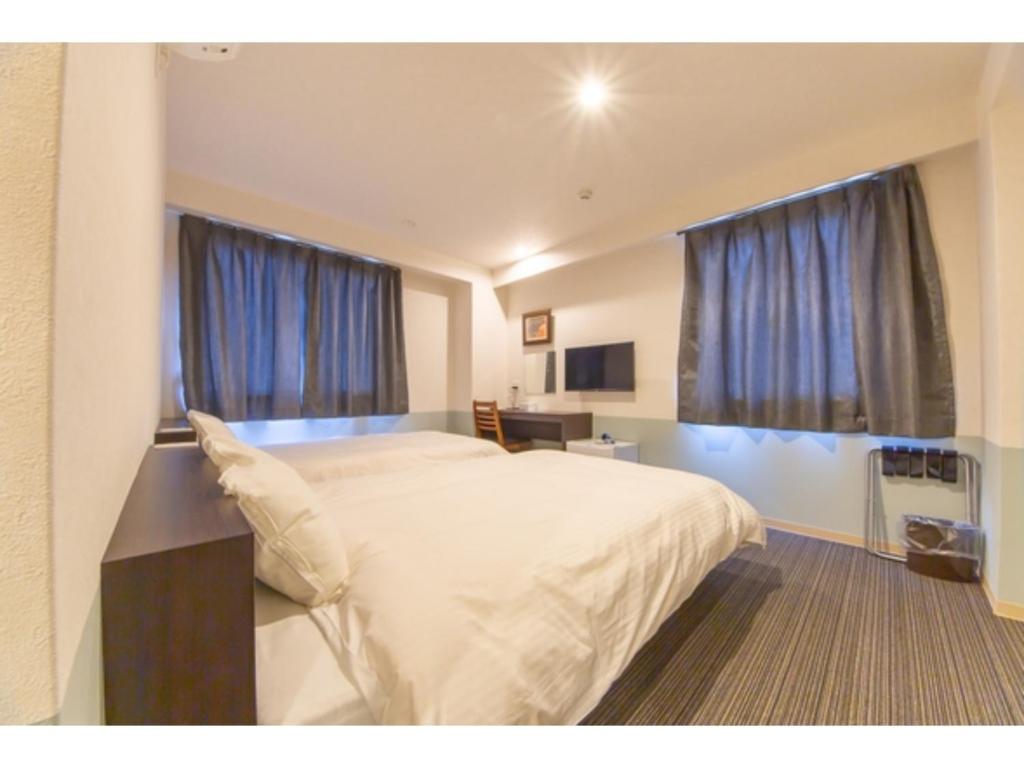 德岛Hotel Taiyonoen Tokushima Kenchomae - Vacation STAY 26351v的卧室配有一张带蓝色窗帘的大型白色床