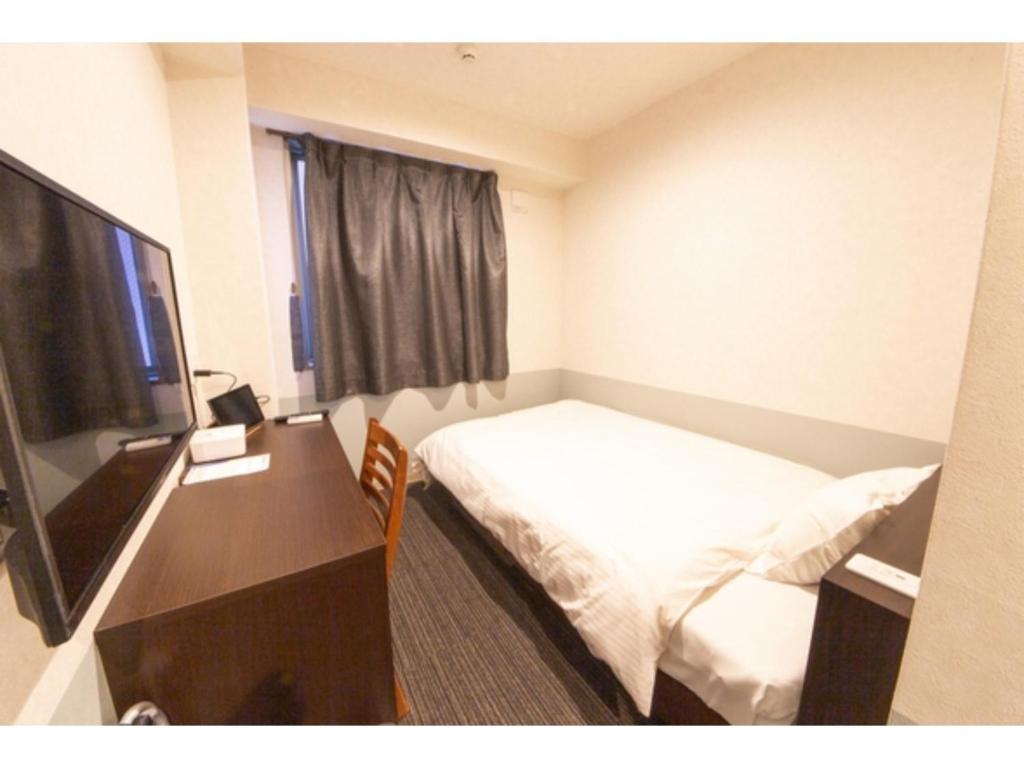 德岛Hotel Taiyonoen Tokushima Kenchomae - Vacation STAY 26338v的酒店客房配有一张床、一张书桌和一台电视。