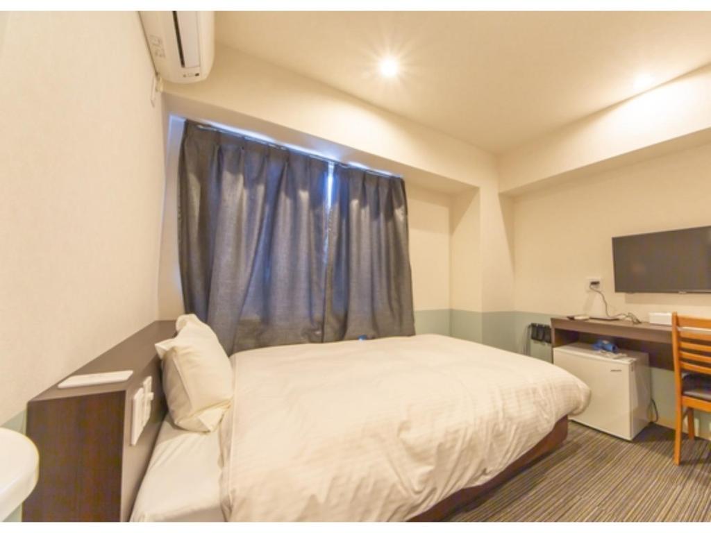 德岛Hotel Taiyonoen Tokushima Kenchomae - Vacation STAY 26340v的一间卧室配有一张床、一张书桌和一个窗户。