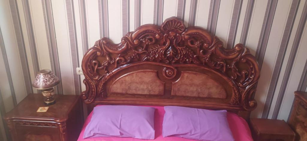 第比利斯GEO Vake Guest House的一张带华丽木制床头板的床铺,配有紫色床单
