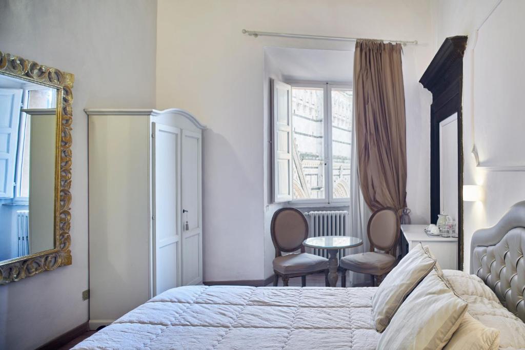 锡耶纳马尼菲科宫殿住宿加早餐旅馆的卧室配有一张床和一张桌子及椅子