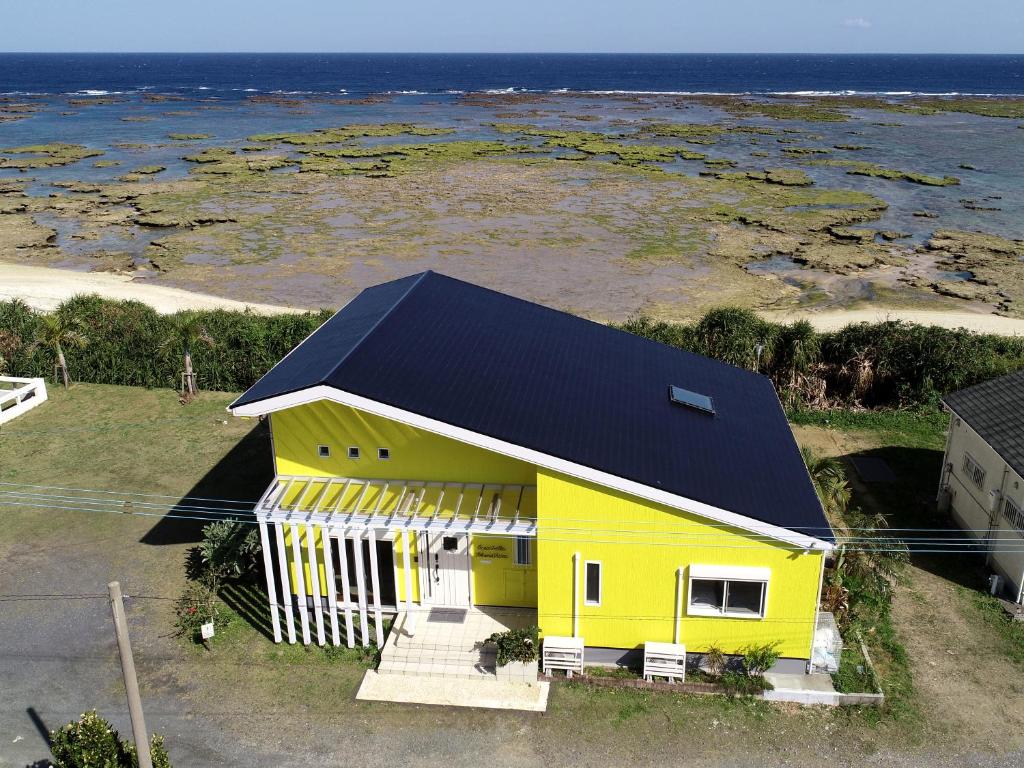 德之岛オーシャンヴィラ徳之島-Ocean Villa Tokunoshima-的黑色屋顶和海洋的黄色房子