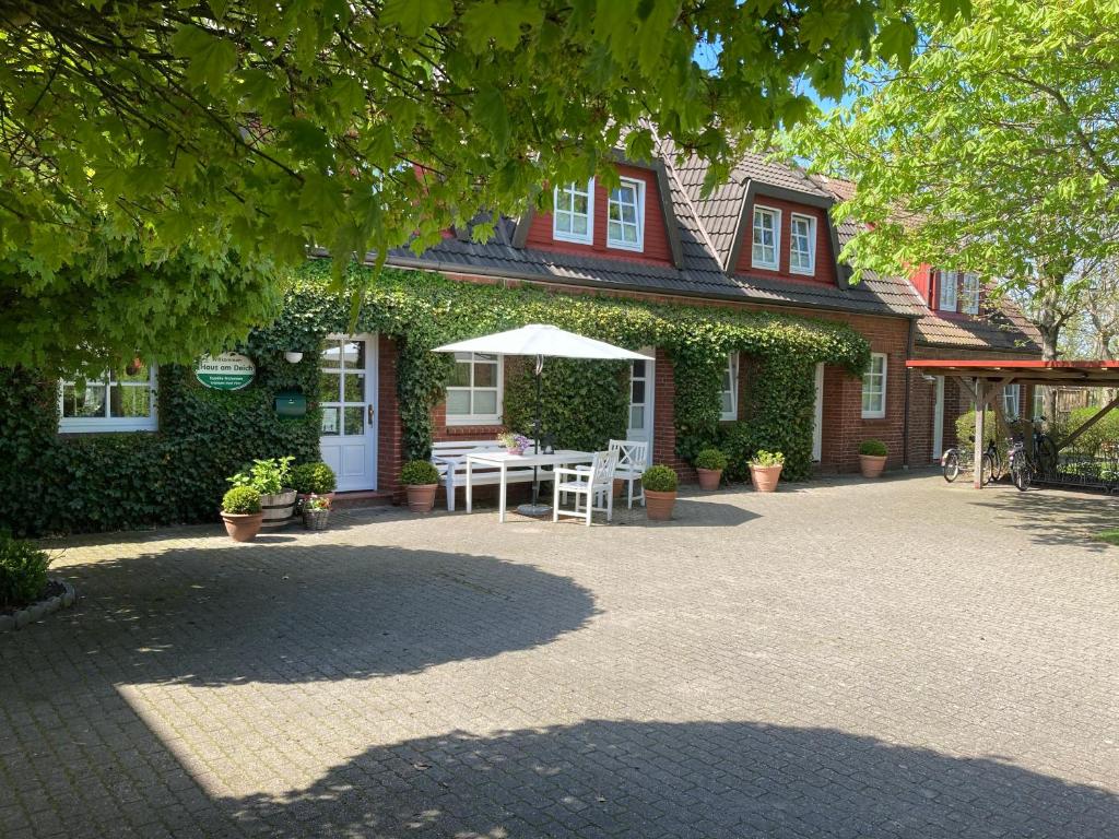 UtersumHaus am Deich的房屋设有带桌子和遮阳伞的庭院