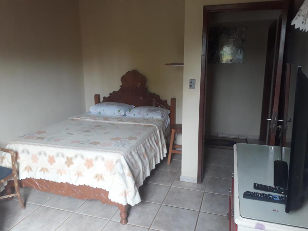沙帕达-杜斯吉马朗伊斯Casa das Flores的一间卧室配有一张床,并在一间客房内配有电视。