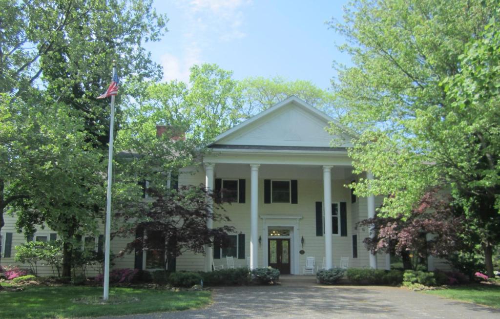 桑达斯基Farrell House Lodge at Sunnybrook Trout Club的前面有美国国旗的白色房子
