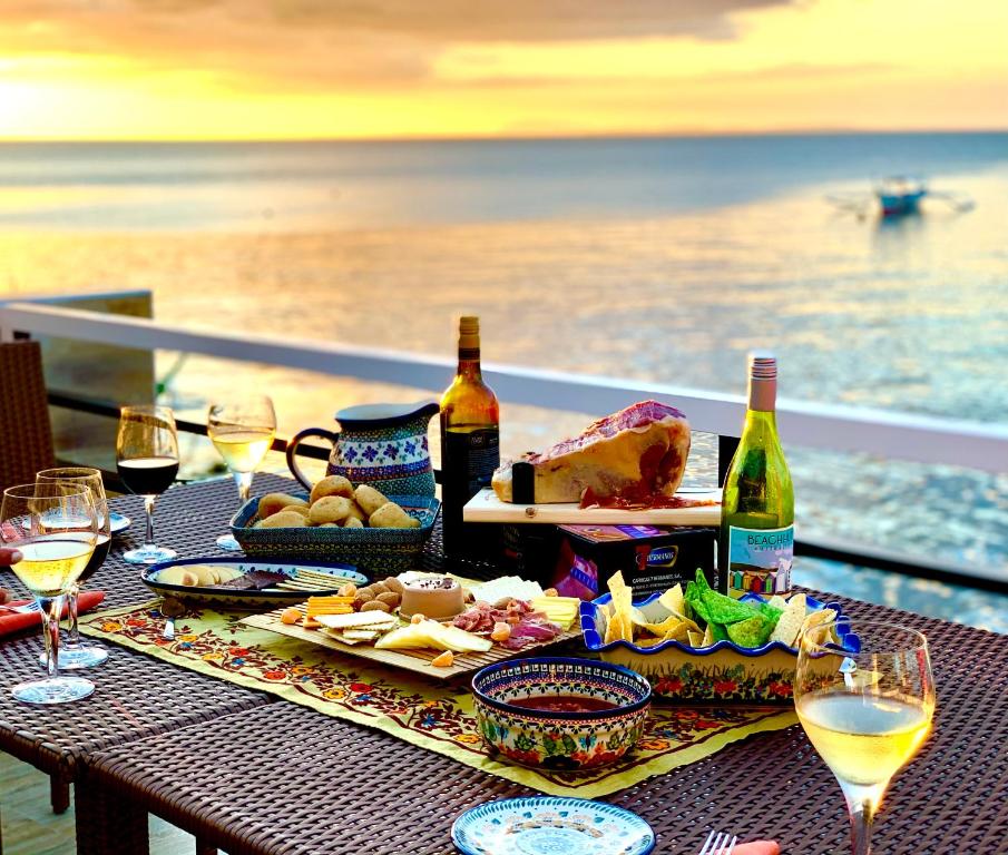 八打雁PamAnilao and Padoy's Dive Camp的阳台上的桌子上摆放着食物和葡萄酒