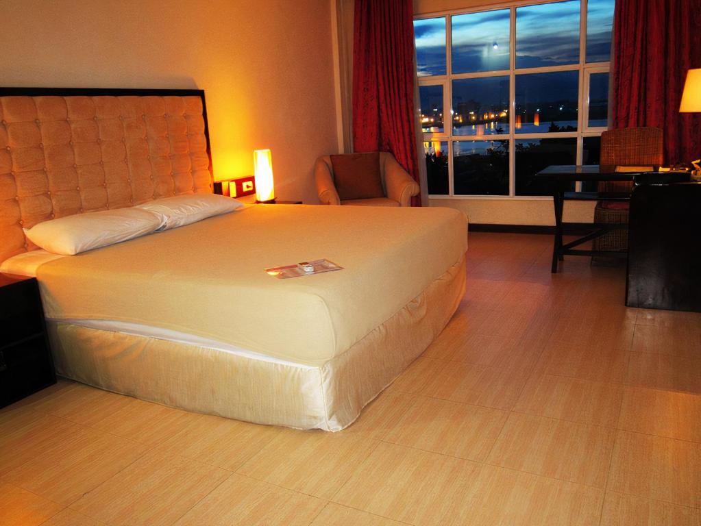 麦克坦Cebu Dulcinea Hotel and Suites-MACTAN AIRPORT HOTEL的酒店客房设有床和窗户。