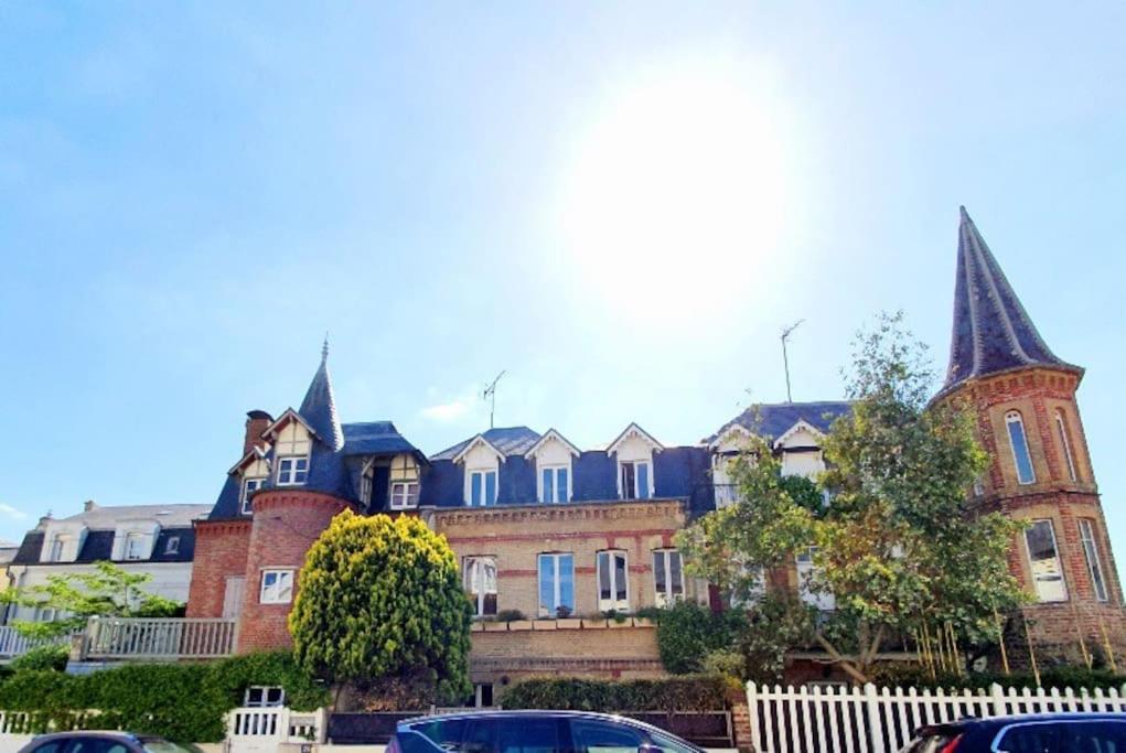 多维尔Villa Bon Accueil的一座带尖顶的大型砖砌建筑,前面设有停车位