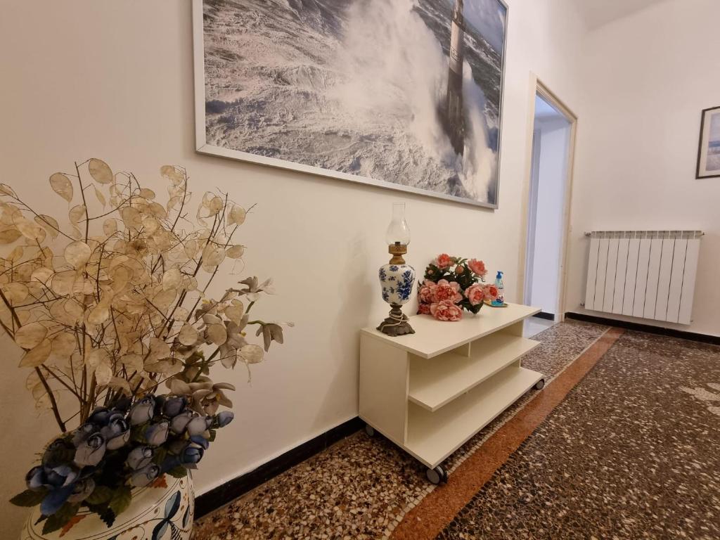 热那亚WOW HOME 2 - 175 mq - posteggio privato - davanti porto traghetti - fino a 10 posti letto - balcone的一间房间,墙上挂着一张带鲜花的桌子和一张照片