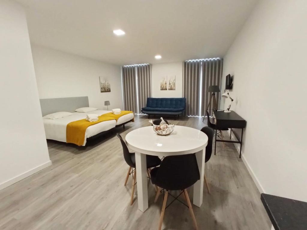 丰沙尔Tanoeiros Studios的客房设有一张床和一张白色的桌子及椅子。