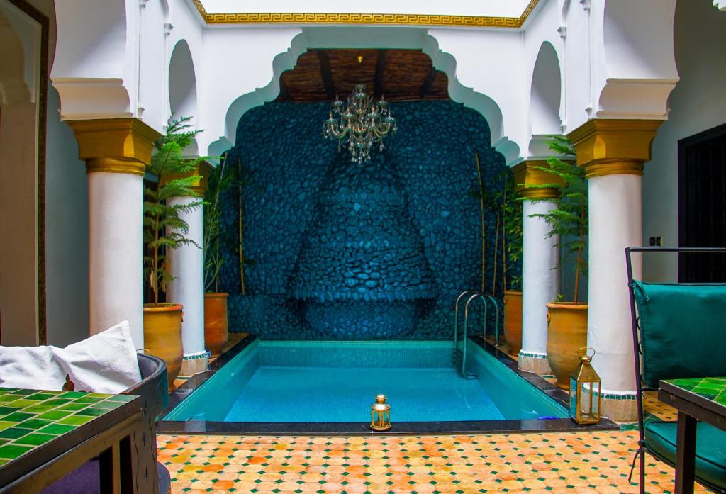 马拉喀什Riad L'Orchidée Suites & Spa的一座带喷泉的建筑中的游泳池
