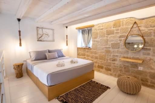 卡尔帕索斯Grannys Luxury Villas的一间卧室设有一张大床和石墙