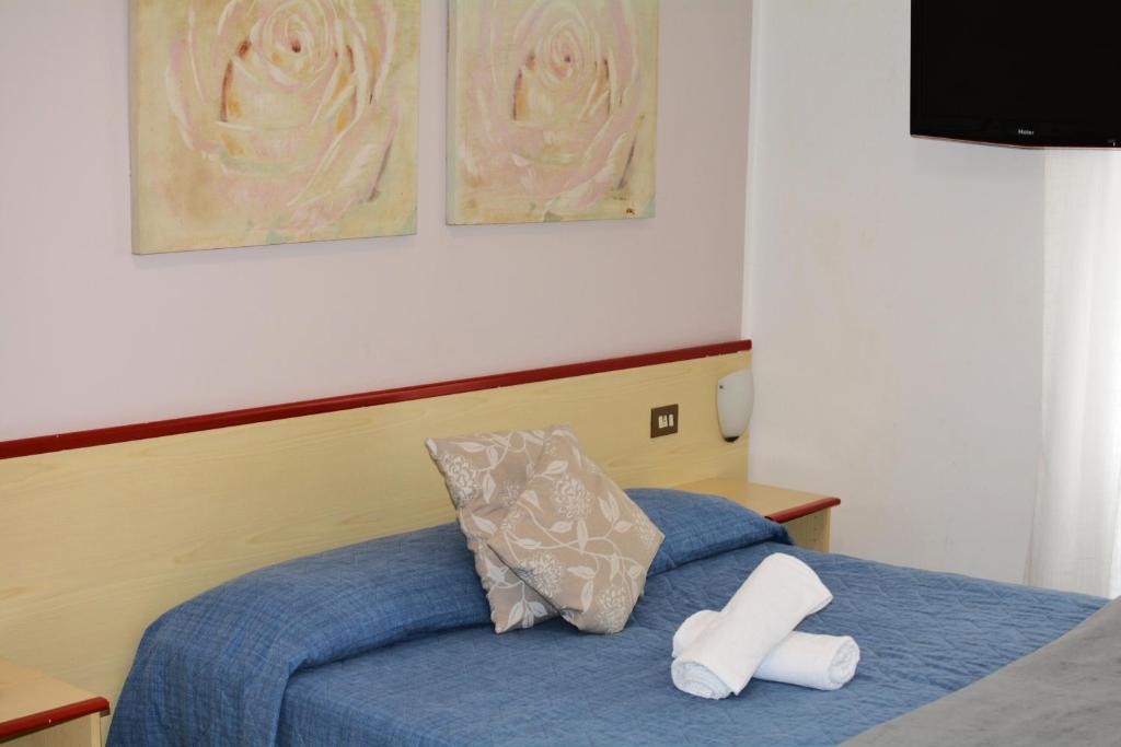 瓦拉泽HOTEL LA MADUNINA的卧室配有蓝色的床和白色枕头
