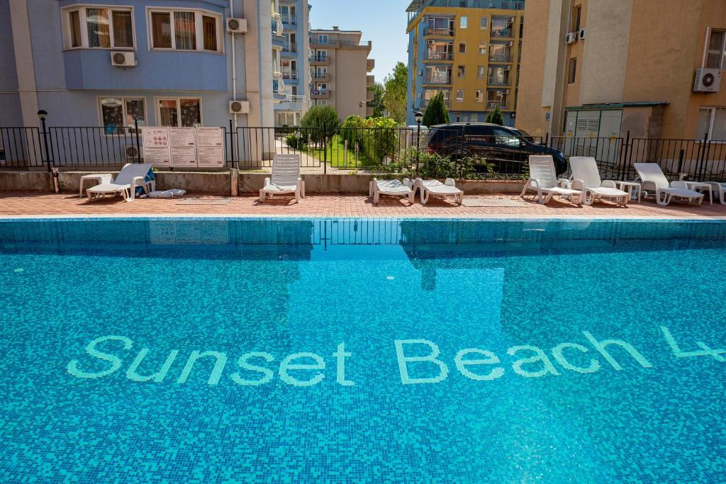阳光海滩Sunset Beach - Menada Apartments的一个带躺椅的游泳池,酒店标志
