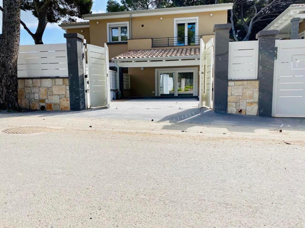 皮诺港Nuova Residenza dei 7 Pini a pochi passi dal mare的一座带白色门和车道的大房子