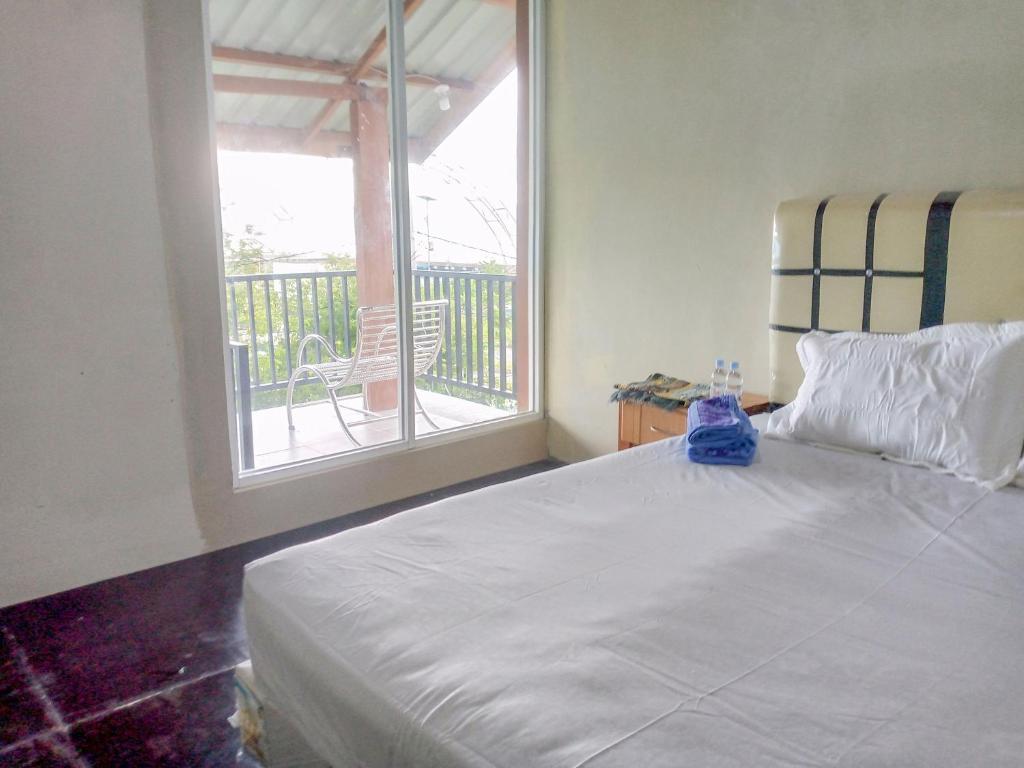 Kota Bawah TimurDeeva Homestay Syariah RedPartner的一间带白色床的卧室和一个阳台