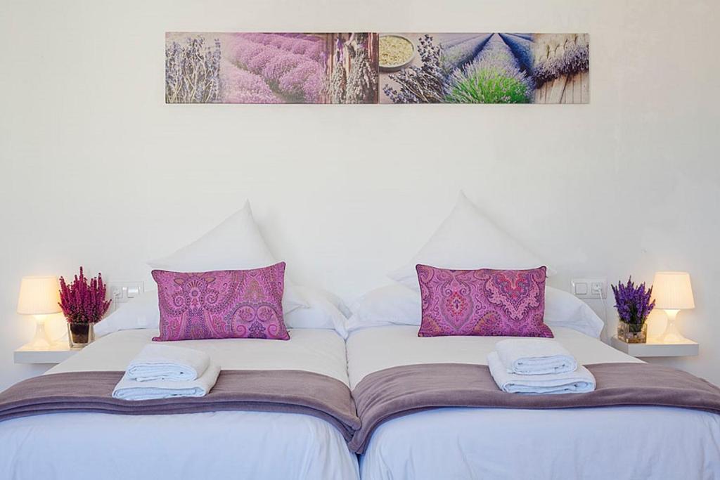 巴塞罗那帕拉勒怡人套房酒店的白色的床,配有紫色枕头和毛巾