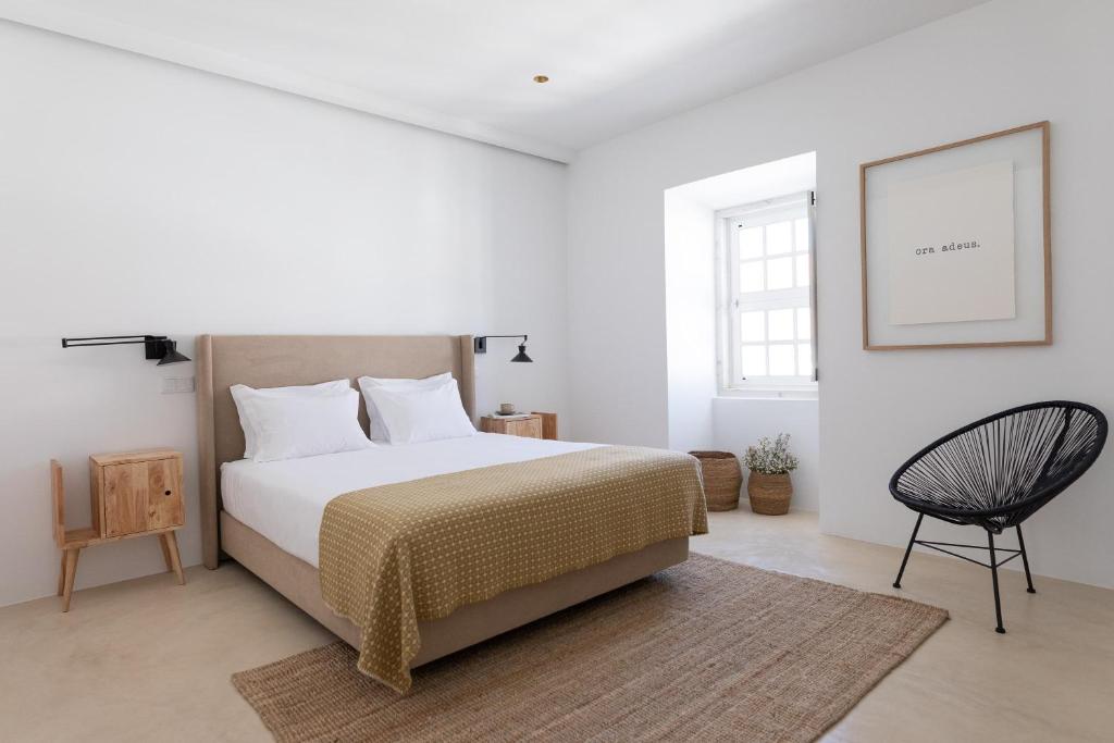 埃斯特雷莫斯Casa do Gadanha的白色卧室配有床和椅子