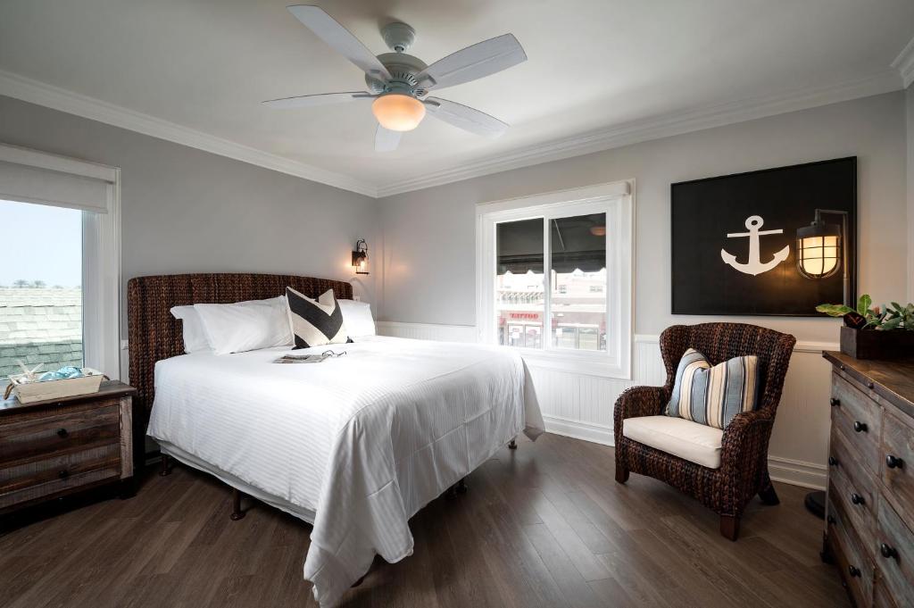 纽波特海滩纽波特海滩酒店 的一间卧室配有一张带吊扇和椅子的床