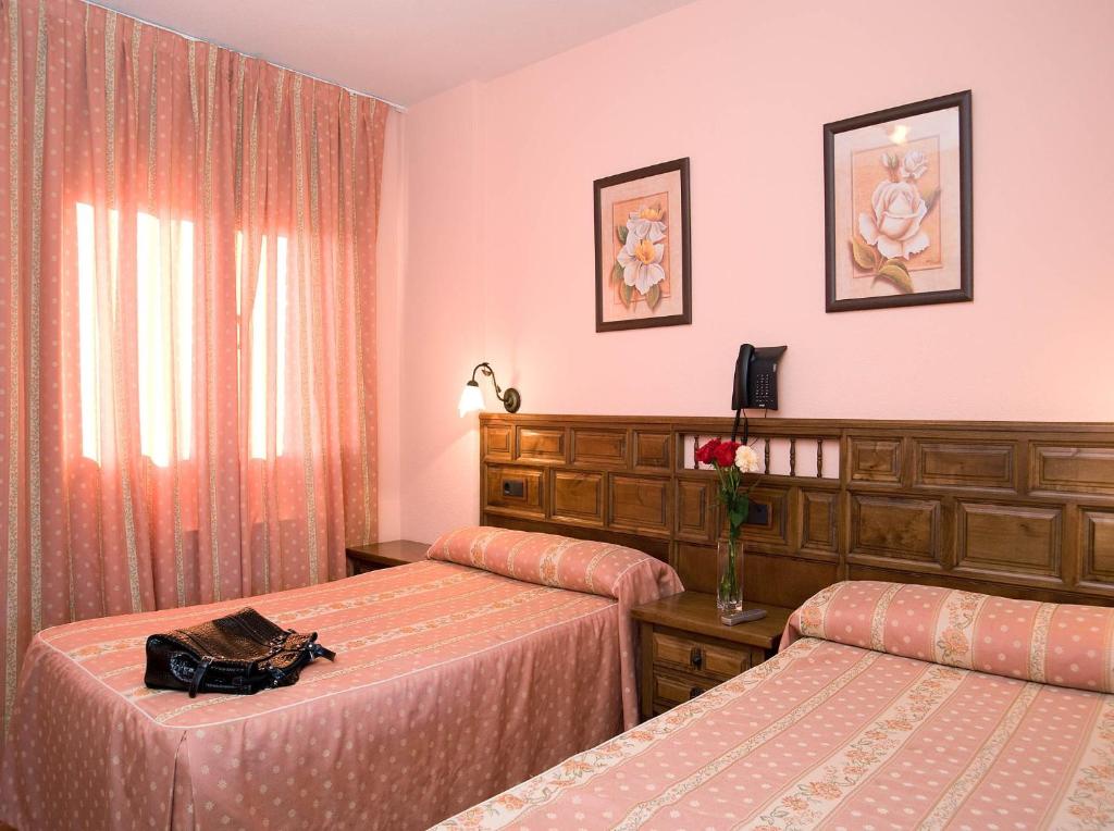 Humanes维多利亚乡村酒店的配有粉红色墙壁的酒店客房的两张床
