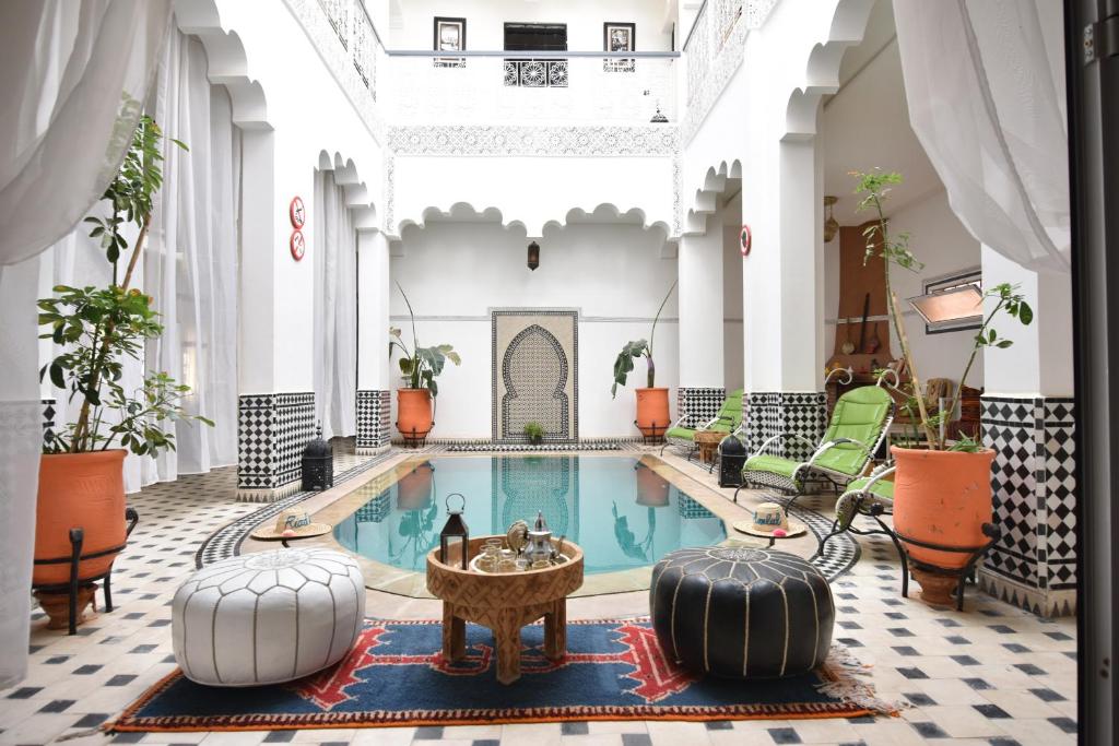 瓦尔扎扎特Hotel Riad Amlal的大堂内带桌椅的酒店游泳池
