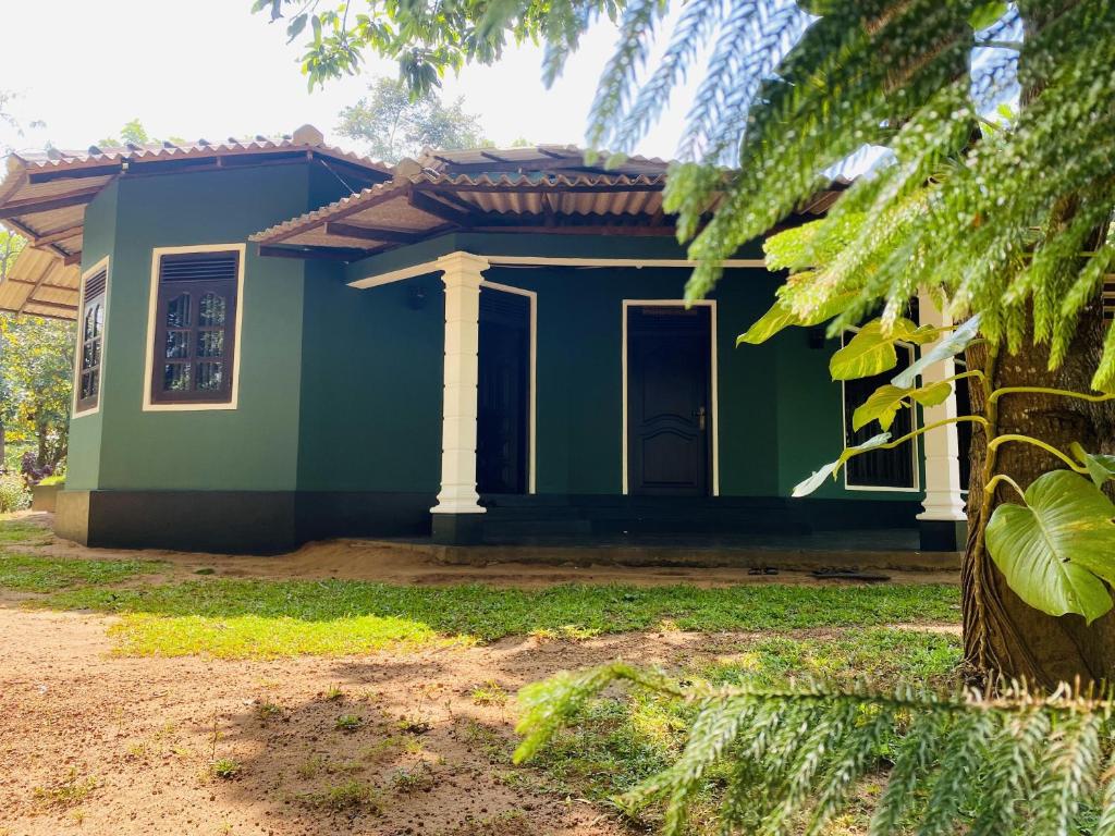 锡吉里亚Sigiri Siesta Homestay的前面有一棵树的小绿色房子