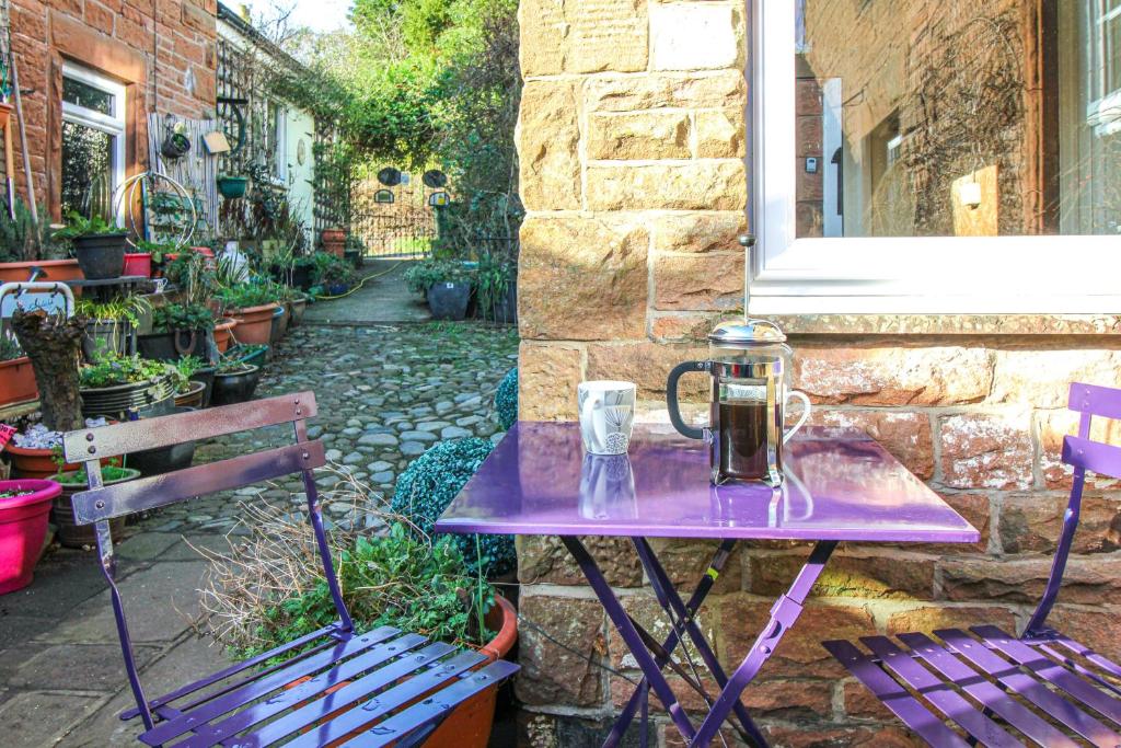 Armathwaite2 Eden Grove Cottages的一张紫色桌子,上面有一壶,旁边是两长凳