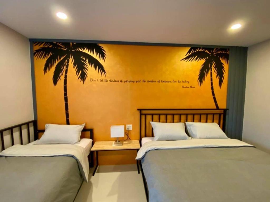 Ban Pak Nam Krasaeบ้าน ชลรพี Baan Chonrapee的墙上棕榈树间内的两张床