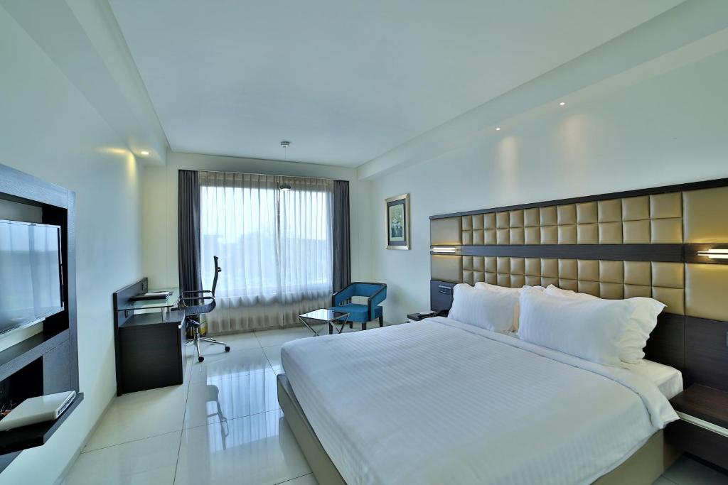 艾哈迈达巴德HOTEL G EXPRESS Formerly Known as TGB Express的酒店客房设有一张大床和一张书桌。