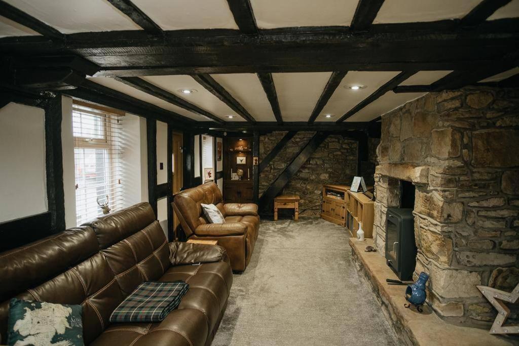 CamertonWILSONS COTTAGE - 2 Bed Classic Cottage located in Cumbria with a cosy fire的带沙发和石制壁炉的客厅
