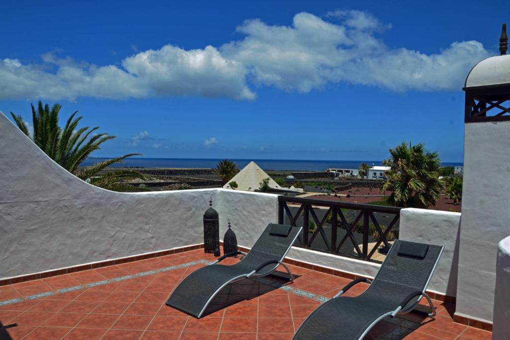 MalaHome Casa Sueño in the Village of Mala的两把椅子坐在俯瞰着大海的庭院