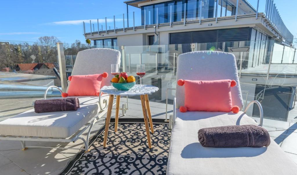 巴拉通雷勒Lelle Marine Resort Voila Apartman的阳台配有两把椅子和一张带一碗水果的桌子。