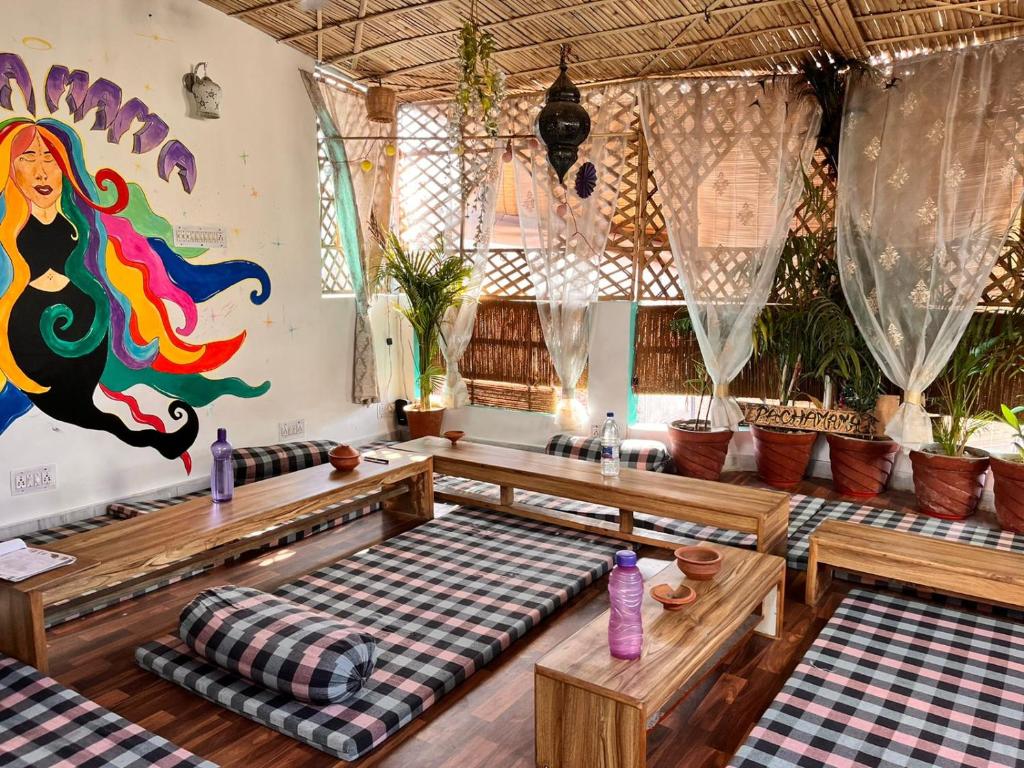 斋浦尔Pachamama Hostel的一间设有长椅的房间和墙上的绘画