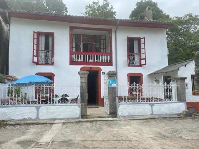 RalesEl Requexu de Rales的白色的房子,设有红色的窗户和栅栏