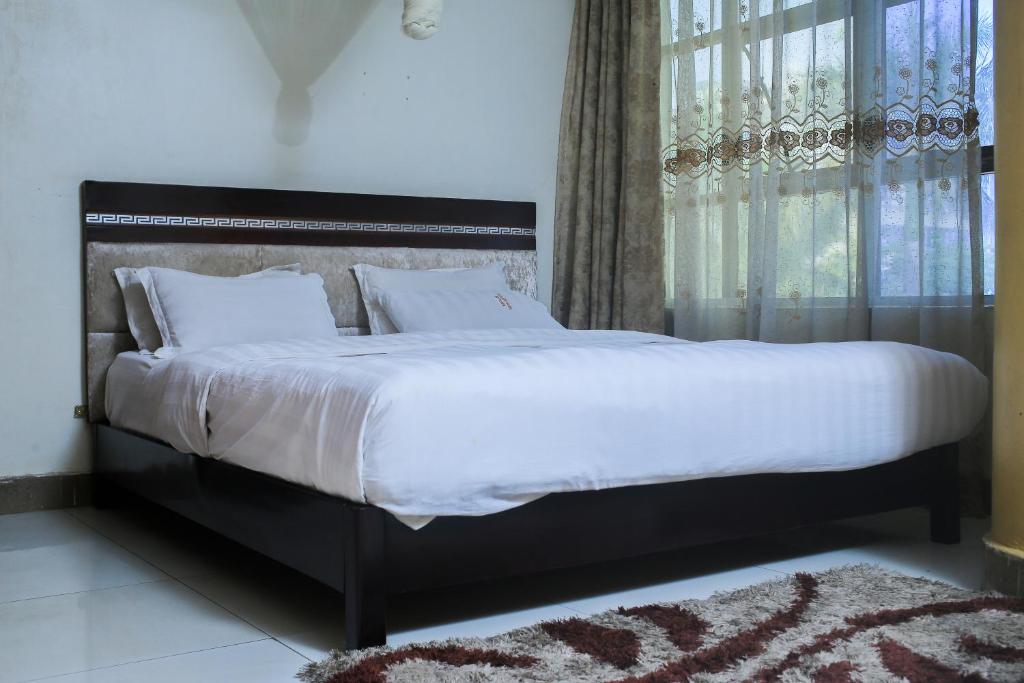 坎帕拉Steric Hotel Kampala的卧室配有一张带白色床单的大床和窗户。