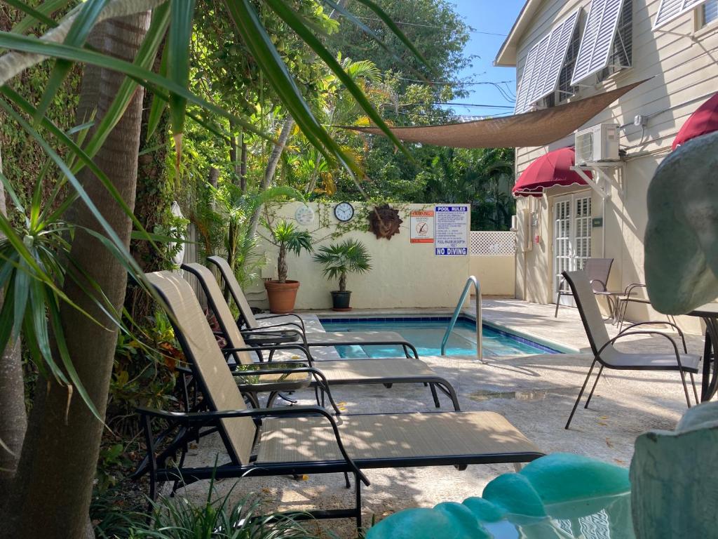 基韦斯特Authors Key West Guesthouse的一组椅子坐在游泳池旁