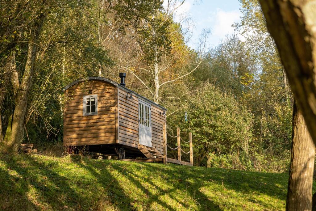 WinshamSomerset Shepherds Huts的坐落在郁郁葱葱的绿色田野顶部的小木屋
