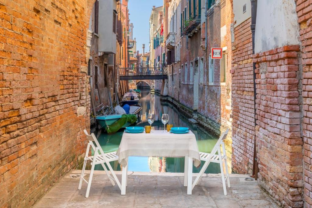 威尼斯Ramo del teatro Canal view的运河小巷中的桌椅