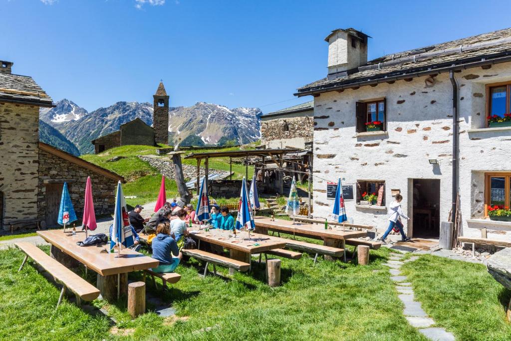 布鲁西奥Rifugio Alpe San Romerio的一群坐在大楼前野餐桌上的人