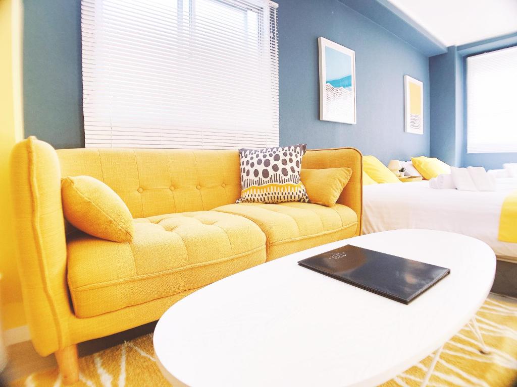 广岛OUCHI HOTEL Nagarekawa with Dogs的客厅配有黄色的沙发和桌子