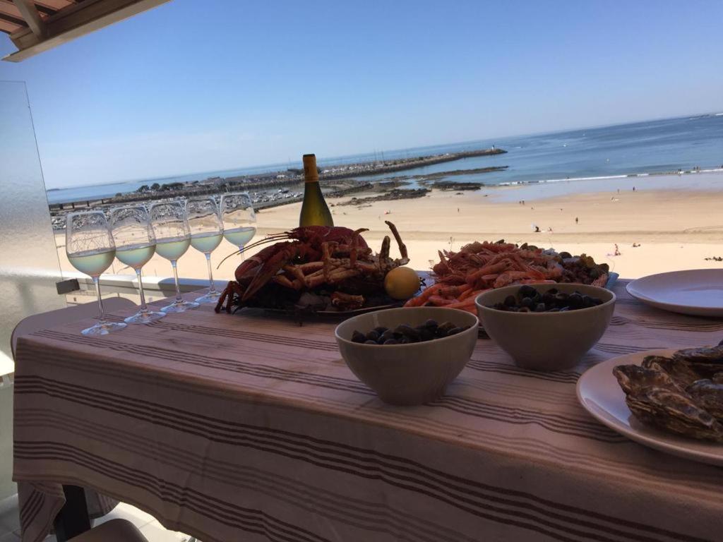 波尔尼谢Superbe vue mer Pornichet, au 5e + parking couvert的海滩上一张桌子,上面放着盘子和酒杯