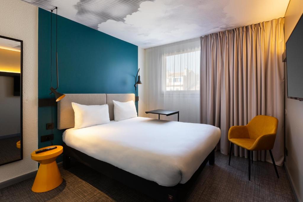 马赛Ibis Marseille Centre Prefecture的酒店客房设有一张大床和一张黄色椅子