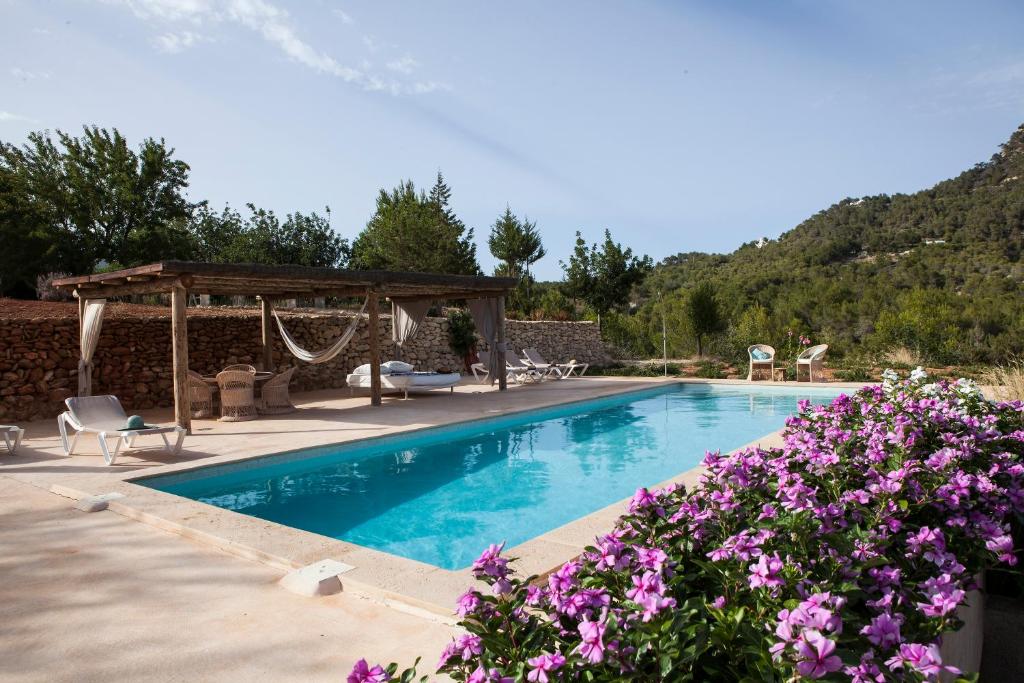 卡拉圣维森特Hacienda Ses Caletes的一个带凉亭和紫色鲜花的游泳池