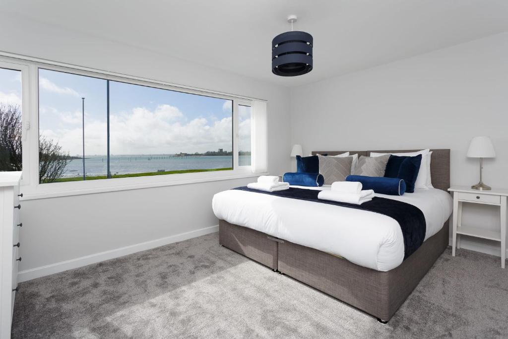 朴次茅斯Castle View - Port Solent Stunning Waterfront House的一间卧室设有一张大床和一个大窗户