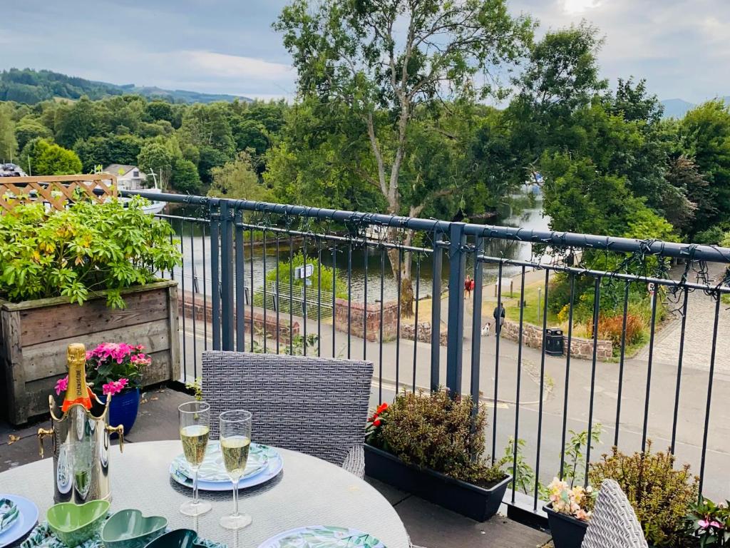 巴洛赫Riverside View Apartment in Balloch, Loch Lomond的阳台上的桌子上摆放着酒杯