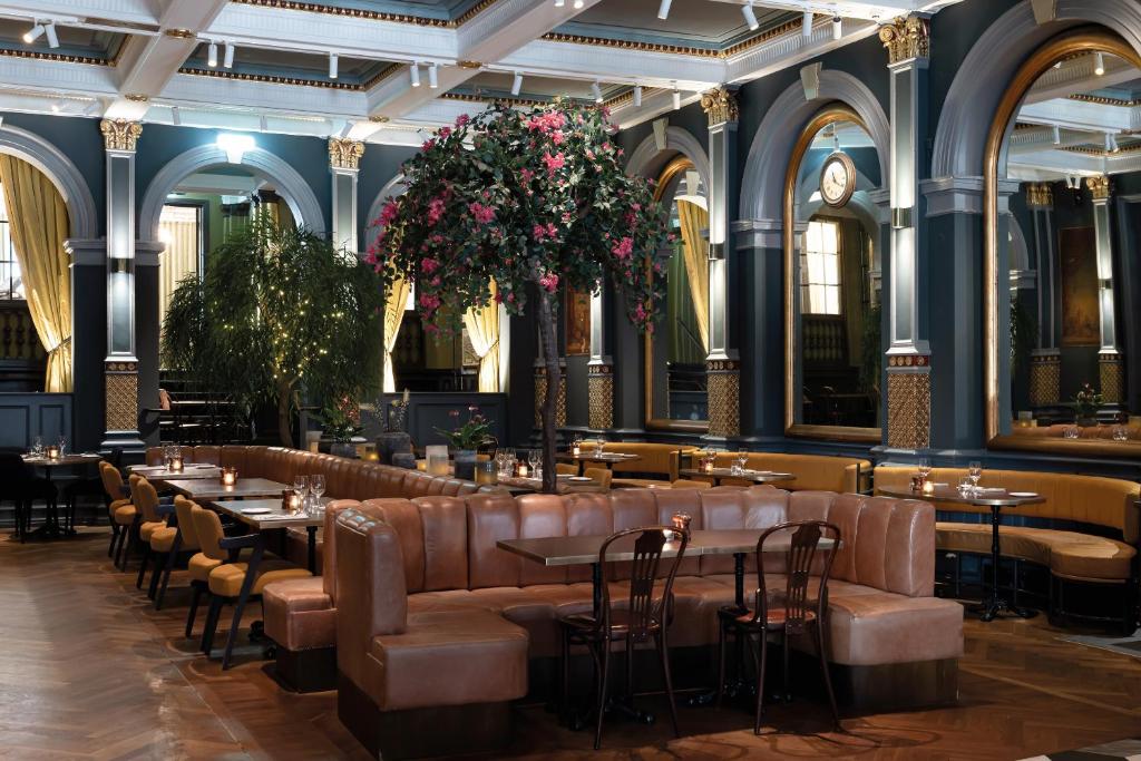 赫尔辛堡瑞典精英酒店的餐厅设有桌子和皮座椅,鲜花盛开