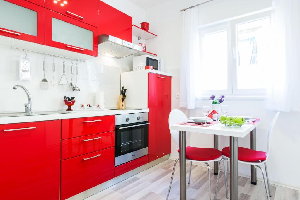 扎达尔Bagi apartment in old town center的红色的厨房,配有白色的桌子和红色的橱柜